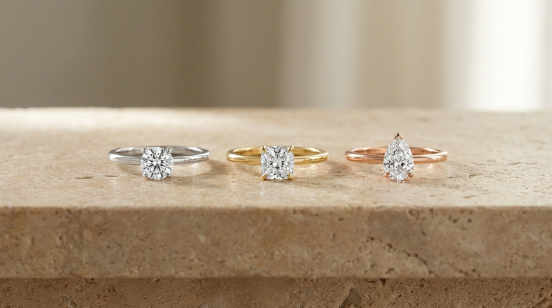 Three fine diamond rings in white gold, yellow gold and rose gold side by side