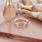 Side profile of a rose gold ring displaying a repeating rhythm of rectangular cut stones and fine seed pearls.