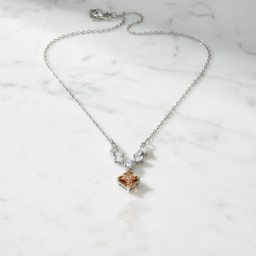 Sculptural baguette accents framing a honeyed lozenge-cut center stone pendant on a polished silver chain.