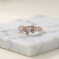 A polished yellow gold ring shaped like a fluid ribbon, featuring a vibrant cerulean blue center stone.