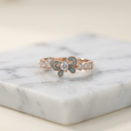 A polished yellow gold ring shaped like a fluid ribbon, featuring a vibrant cerulean blue center stone.