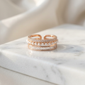 A wide rose gold ring encrusted with three parallel rows of brilliant cut sparkling pavé stones.
