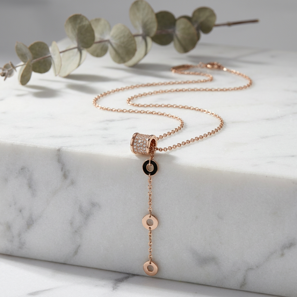 Macro detail of a fine pavé-set cylinder barrel resting on a sleek, fluid rose gold linear drop necklace.