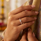 Detailed macro view of a round brilliant center stone held on a high-polish rose gold band with small accent stones.