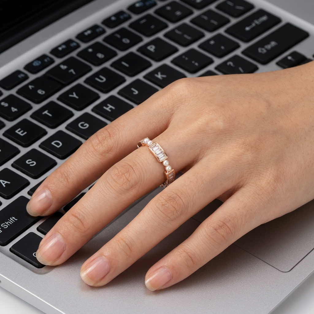 Studio flat lay of a contemporary rose gold eternity band with structured stones and pearls on a white surface.