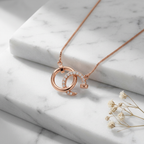 Sculptural rose gold round pendant featuring interlocking industrial circles and a shimmering pavé-accented silhouette.