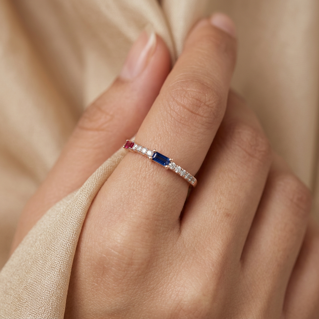 Close-up of a model wearing a slender ruby and sapphire ring in warm rose gold for a curated, modern aesthetic.