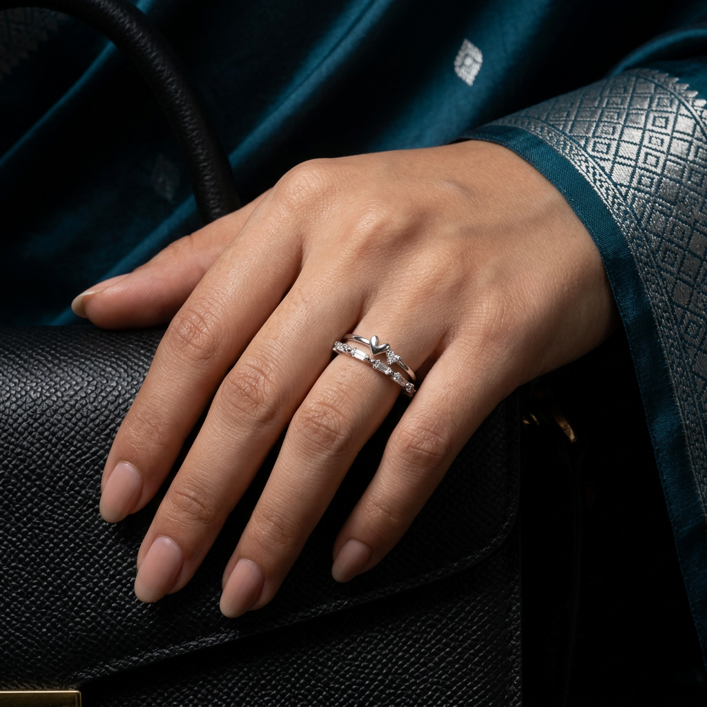 Close-up of a model wearing a tiered silver heart ring on her finger, displaying a sharp, contemporary look.