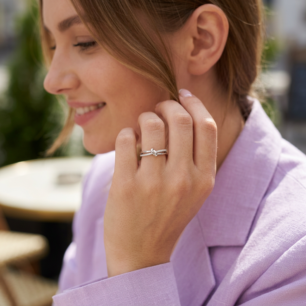 Close-up of a model wearing a silver multi band knot ring, showcasing a fluid interlaced design with brilliant gems.