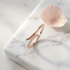 A luxury rose gold open ring with a fluid bypass silhouette and sparkling pavé stone detailing.