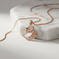 Rose gold necklace for women featuring a sculptural swan pendant inlaid with mother of pearl and pave crystals.