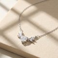 A sterling silver heart necklace for women featuring a central heart-cut stone and a winged marquise diamond cluster.