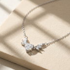 A sterling silver heart necklace for women featuring a central heart-cut stone and a winged marquise diamond cluster.