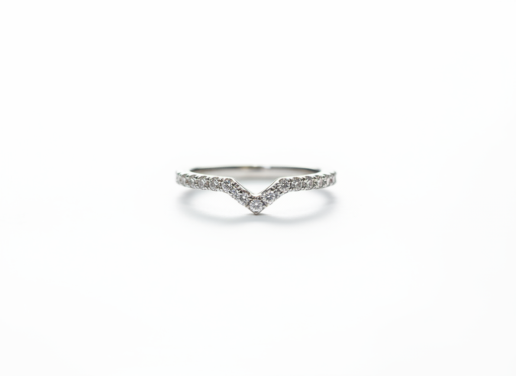 A curated silver stacking ring set anchoring a sharp V-contour pavé band to frame a minimalist jewelry collection.