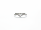 A curated silver stacking ring set anchoring a sharp V-contour pavé band to frame a minimalist jewelry collection.