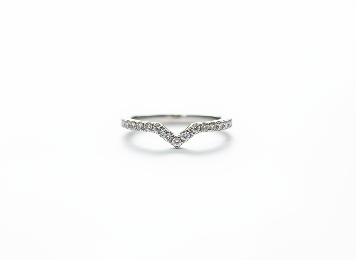 A curated silver stacking ring set anchoring a sharp V-contour pavé band to frame a minimalist jewelry collection.