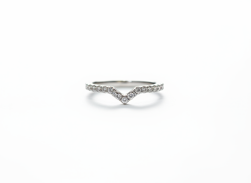 A curated silver stacking ring set anchoring a sharp V-contour pavé band to frame a minimalist jewelry collection.