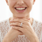 Editorial shot of a woman wearing a large white enamel and gold butterfly statement ring on her finger.