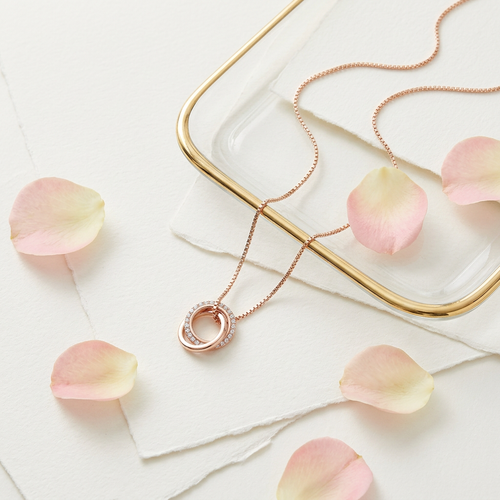A modern interlocking ring pendant necklace crafted in rose gold with a precision-set crystal pavé halo.