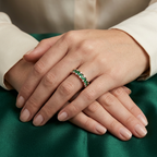 A curated fine jewelry hand stack pairing a green emerald eternity ring with slim rose gold companion bands.