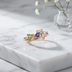 An asymmetric rose gold cluster ring featuring an organic arrangement of pear and marquise gemstones in ocean blue hues.
