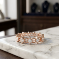 Front studio view of a rose gold eternity band showcasing geometric kite-set princess diamonds with milgrain frames.