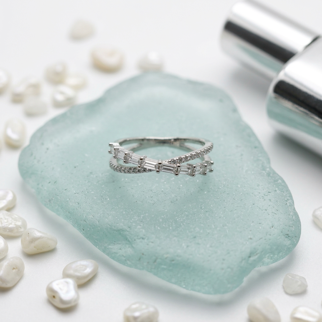 Front view of a sterling silver crossover ring featuring interlocking lines of step cut baguettes and pavé diamonds.