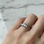 A sculptural silver open wrap ring with sparkling pavé diamonds styled on a model's finger.