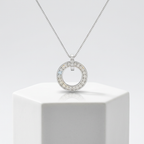 A polished white gold circle pendant featuring pavé-set faceted stones on a refined box chain for layered wear.