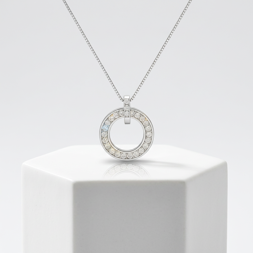 A polished white gold circle pendant featuring pavé-set faceted stones on a refined box chain for layered wear.