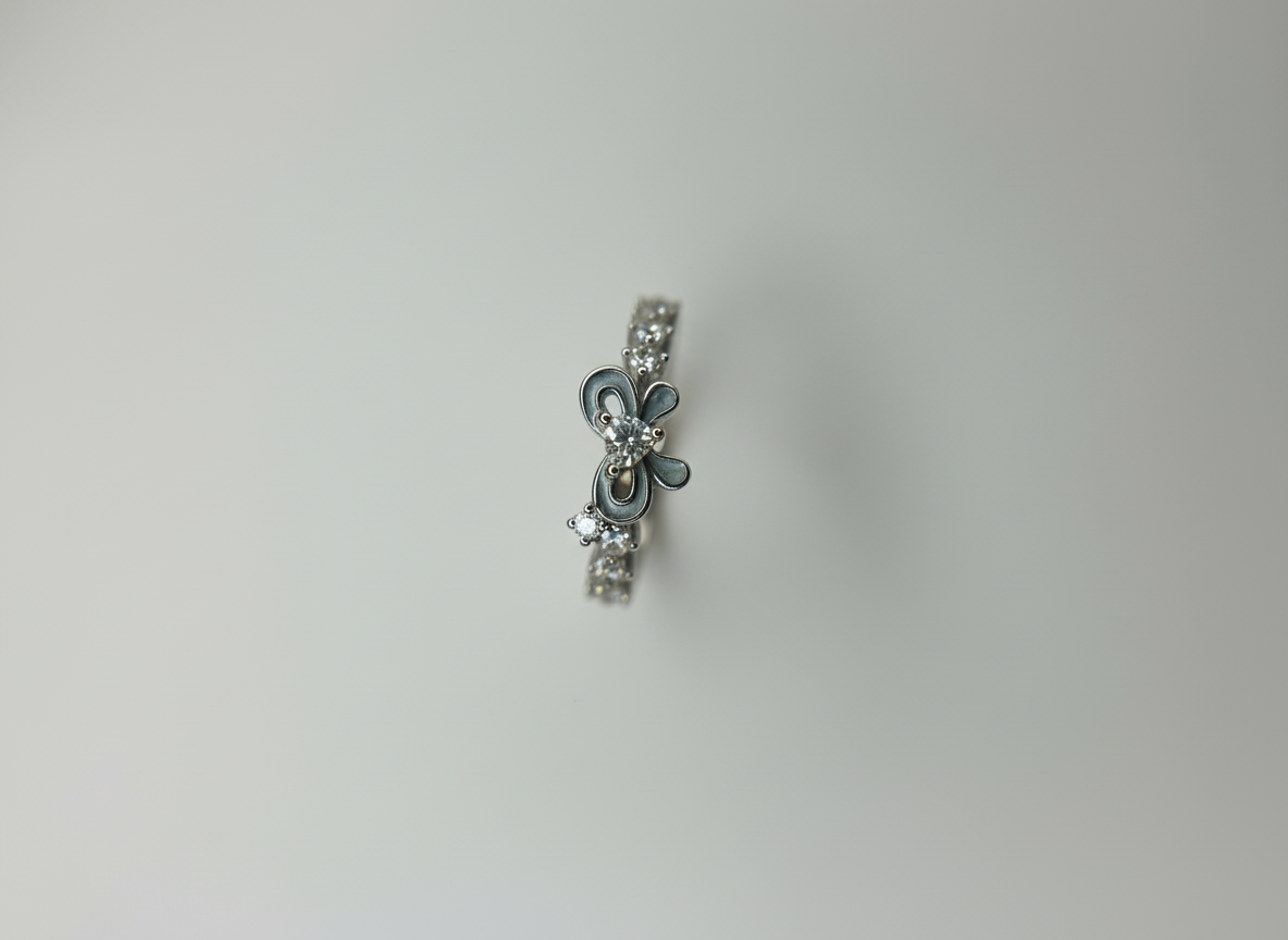 Top-down studio shot of a contemporary black enamel bow ring isolated cleanly on a smooth marble background.