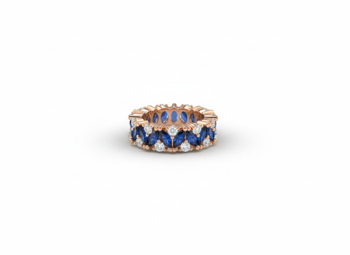 Studio flat lay of a sculptural rose gold band with deep blue stones on a smooth ceramic surface.