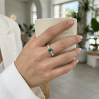 Top-down studio shot of a geometric forest green emerald ring isolated cleanly on a smooth background.
