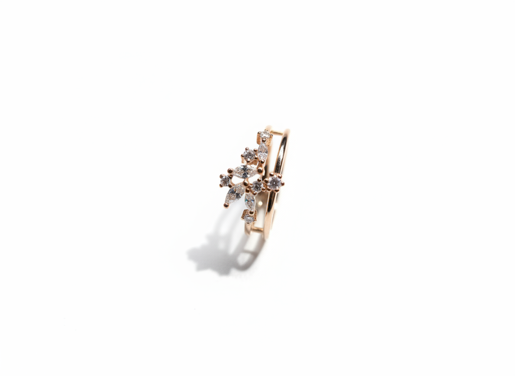 Studio flat lay of a geometric diamond cluster band in polished gold isolated cleanly on a warm marble plate.