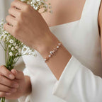 A model wearing the dainty diamond ribbon rose bracelet, illustrating its elegant drape on the wrist with white flowers.