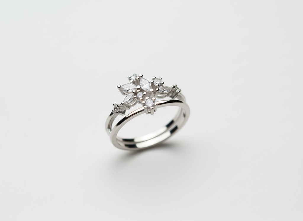 Top-down studio shot of a geometric silver celestial crown ring isolated cleanly on a smooth premium stone tile.