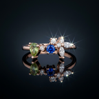 Editorial view of an asymmetric rose gold cluster ring with pear and marquise cut blue gems.