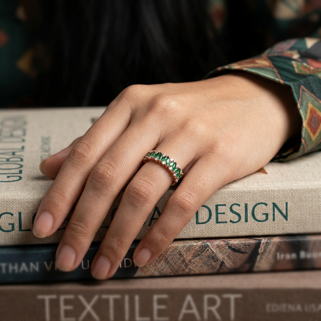 Editorial shot of a model wearing a rose gold eternity band set with vibrant green emeralds and clear diamonds.