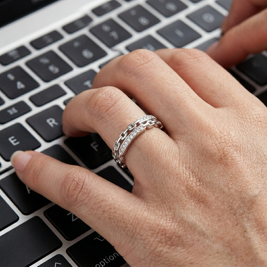 Close-up of a model wearing a heavy silver interlocking link ring on her finger for a modern industrial jewelry look.