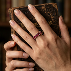 Editorial shot of a model wearing an interlocking rose gold eternity band with vivid red rubies and clear gemstones.