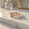 An elegant rose gold-plated sterling silver mariposa pearl ring featuring a central butterfly, graduated pearls, and a pear-cut lab-grown diamond.