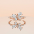 Studio product shot of a rose gold pavé band featuring a sculptural butterfly wing silhouette of cluster stones.