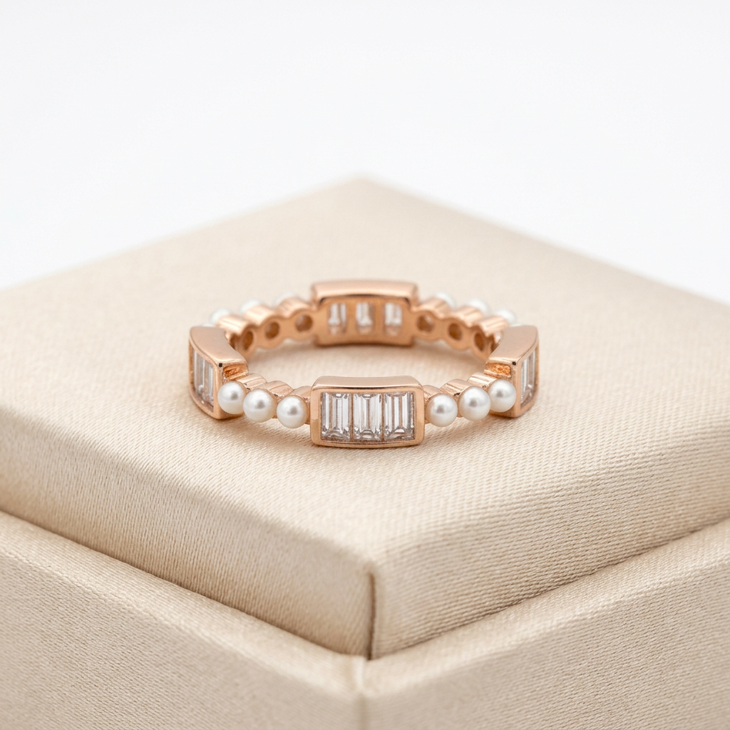 A rose gold eternity ring featuring an alternating textured pattern of baguette cut stones and round white seed pearls.