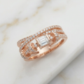 An architectural multi-layered statement ring featuring sweeping twisting bands that create a sculptural silhouette, beautifully anchoring a singular step-cut stone between elegant pavé-encrusted diamond lines.