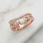 An architectural multi-layered statement ring featuring sweeping twisting bands that create a sculptural silhouette, beautifully anchoring a singular step-cut stone between elegant pavé-encrusted diamond lines.