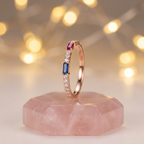 Profile view displaying the slender, modern gold silhouette and vibrant geometric gems of a ruby and sapphire ring.