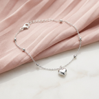 High-polish silver chain bracelet featuring structural beads and a central puffed heart charm pendant.