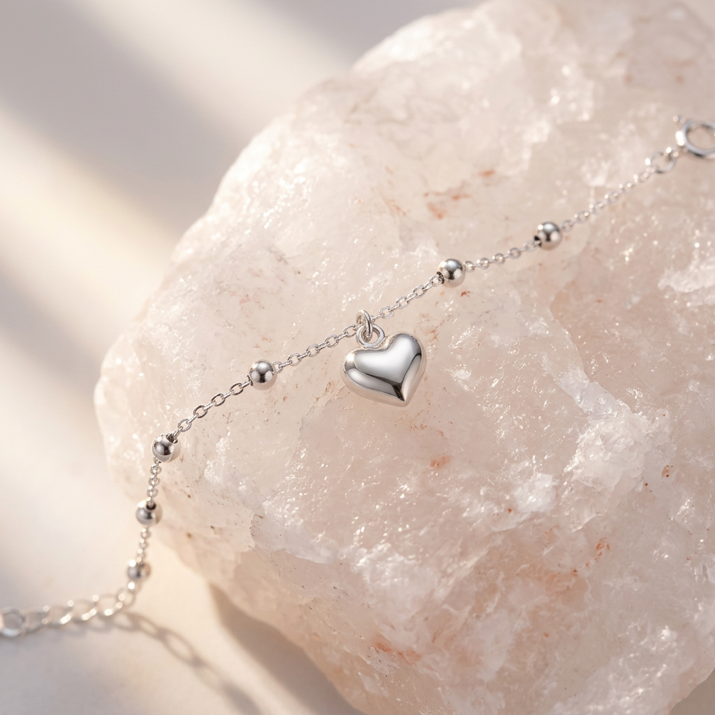 Close-up highlighting the polished, modern metalwork of a sculptural silver puffed heart charm.