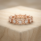 Studio flat lay of a designer rose gold kite diamond stacker ring isolated cleanly on a warm stone surface.