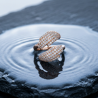 Macro photo focusing on the tiny, shimmering pavé stones set into the hand motifs of an open bypass ring.